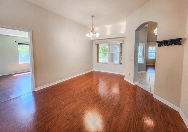 8 Burning Sands Ln, Palm Coast, FL 32137 - empty room featuring arched walkways, wood finished floors, a chandelier, and baseboards