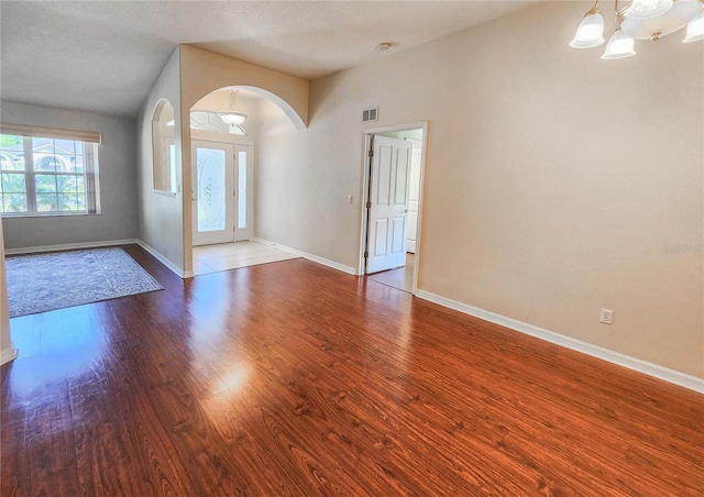 unfurnished room featuring vaulted ceiling, wood-type flooring, and a textured ceiling