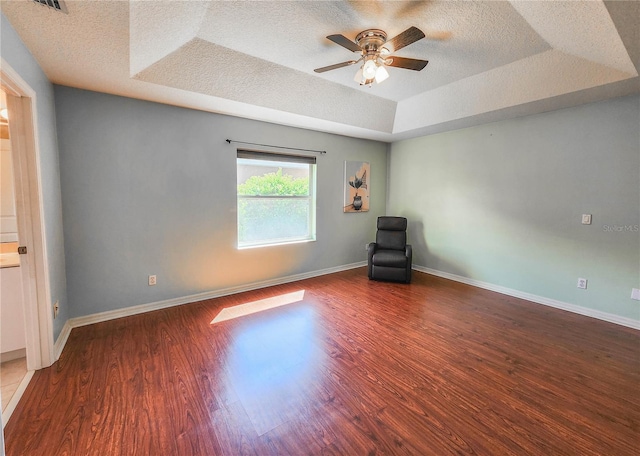 interior space with hardwood / wood-style floors, a textured ceiling, a tray ceiling, and ceiling fan