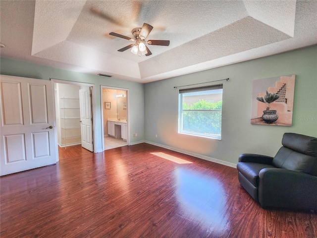 interior space with ensuite bathroom, a raised ceiling, ceiling fan, a spacious closet, and wood-type flooring