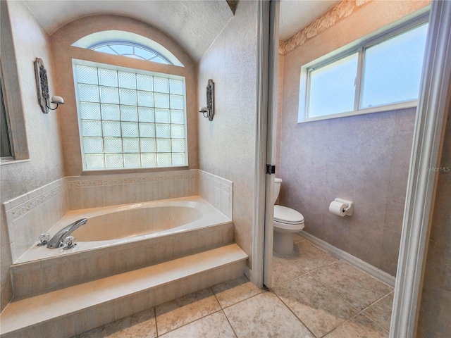 bathroom featuring tile patterned floors, a bathing tub, plenty of natural light, and toilet