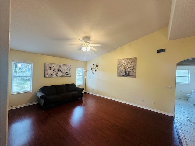 living room featuring a textured ceiling, ceiling fan, dark wood-type flooring, and vaulted ceiling