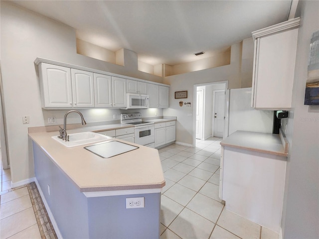 kitchen with kitchen peninsula, white appliances, sink, light tile patterned floors, and white cabinetry