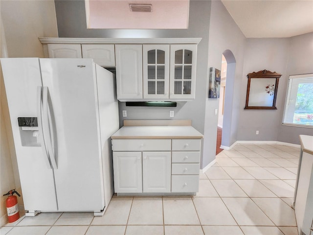 kitchen featuring white cabinetry, white fridge with ice dispenser, and light tile patterned floors