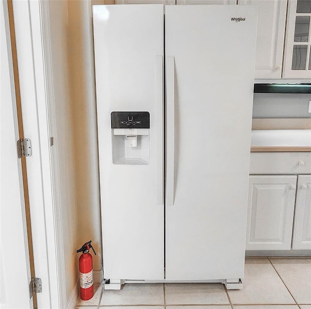 interior details with white cabinetry, white fridge with ice dispenser, and light tile patterned floors