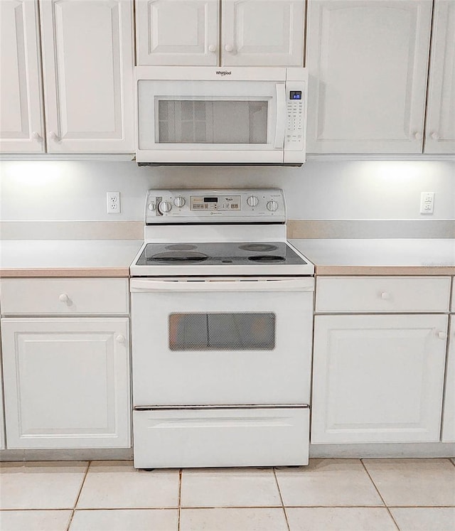 kitchen with white cabinets, light tile patterned floors, and white appliances