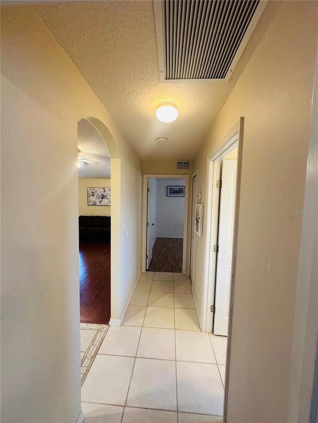 8 Burning Sands Ln, Palm Coast, FL 32137 - hallway featuring light tile patterned floors, arched walkways, a textured ceiling, and baseboards