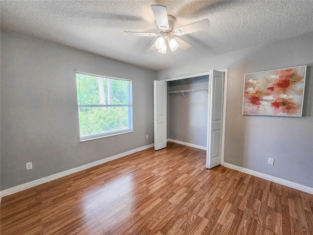 unfurnished bedroom featuring ceiling fan, light wood-type flooring, a textured ceiling, and a closet