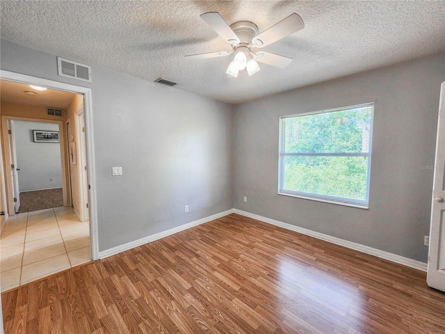 empty room featuring ceiling fan, a textured ceiling, and light wood-type flooring