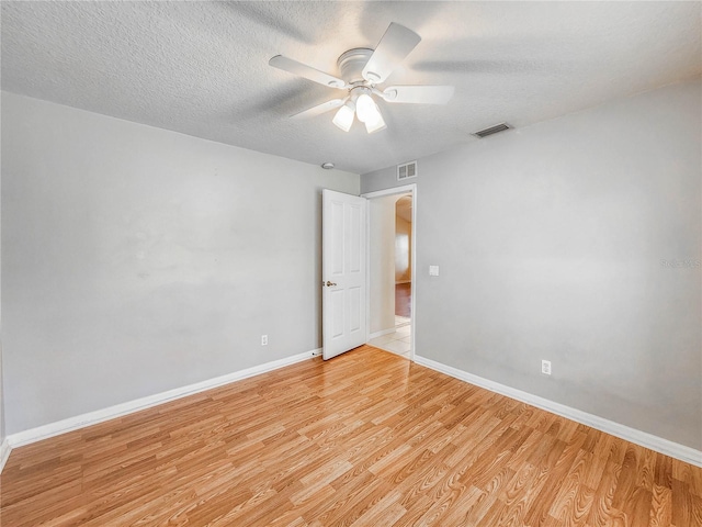 spare room with a textured ceiling, light wood-type flooring, and ceiling fan