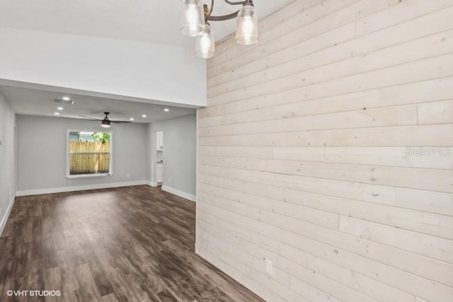 interior space with hardwood / wood-style floors, ceiling fan with notable chandelier, and wooden walls