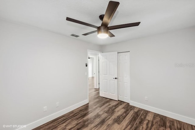 unfurnished bedroom featuring a closet, dark hardwood / wood-style floors, and ceiling fan