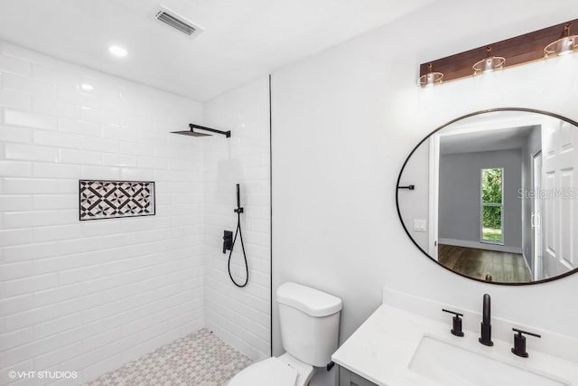 bathroom featuring vanity, toilet, and tiled shower