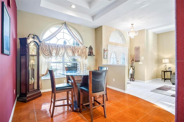 tiled dining area with a notable chandelier and a tray ceiling