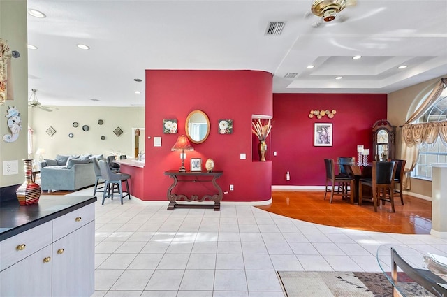 interior space with a raised ceiling and light tile patterned flooring