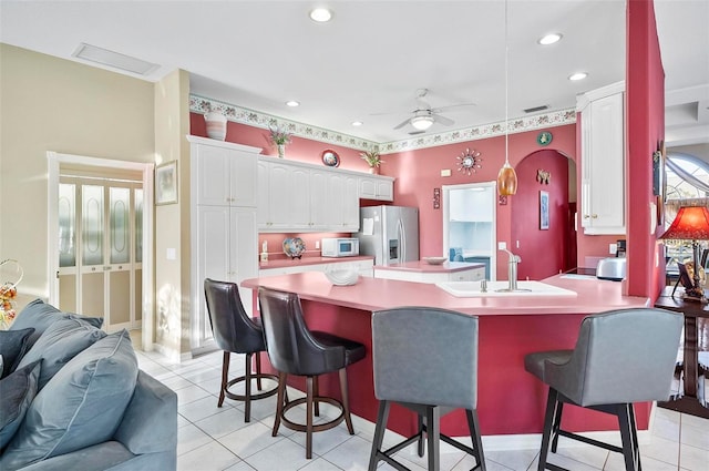 kitchen featuring a kitchen breakfast bar, stainless steel fridge with ice dispenser, plenty of natural light, and white cabinets