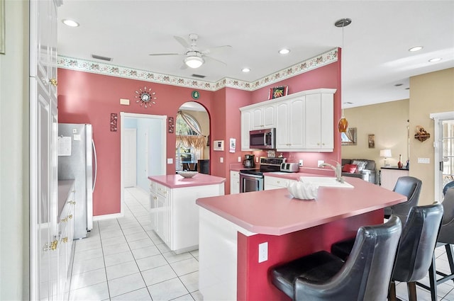 kitchen featuring a breakfast bar, a center island, ceiling fan, appliances with stainless steel finishes, and white cabinetry