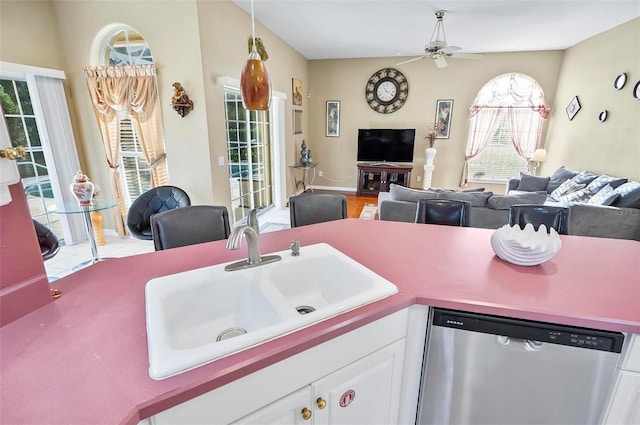 kitchen featuring stainless steel dishwasher, white cabinetry, sink, and a wealth of natural light