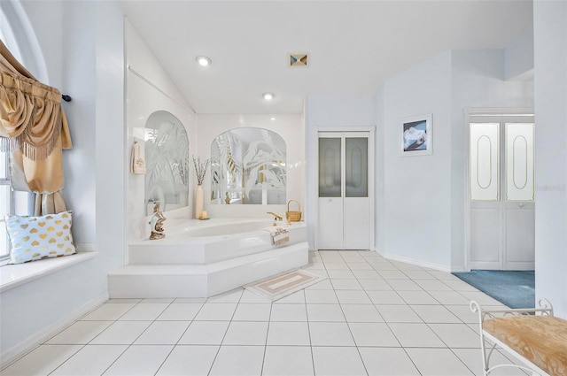 bathroom featuring a washtub, tile patterned floors, and lofted ceiling