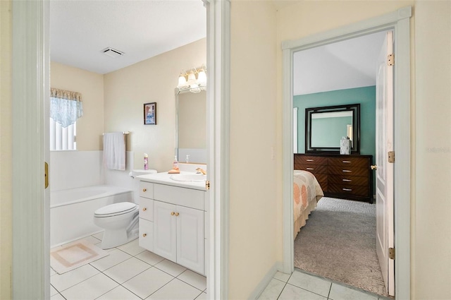 bathroom featuring tile patterned floors, a tub to relax in, vanity, and toilet