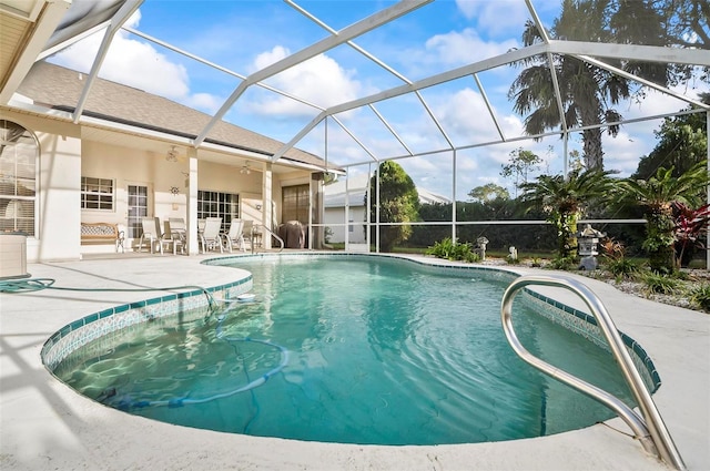 view of swimming pool with ceiling fan, a patio area, and glass enclosure