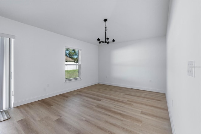 spare room featuring light hardwood / wood-style floors and a notable chandelier