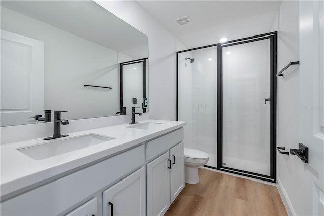 bathroom featuring hardwood / wood-style floors, vanity, toilet, and an enclosed shower