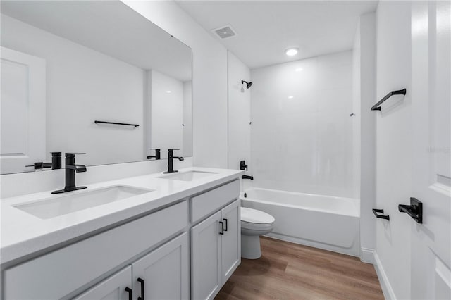 full bathroom featuring tiled shower / bath, vanity, wood-type flooring, and toilet