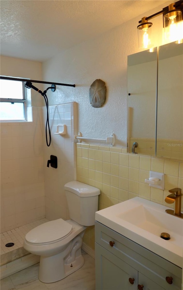 bathroom featuring tile patterned floors, vanity, a textured ceiling, tiled shower, and toilet