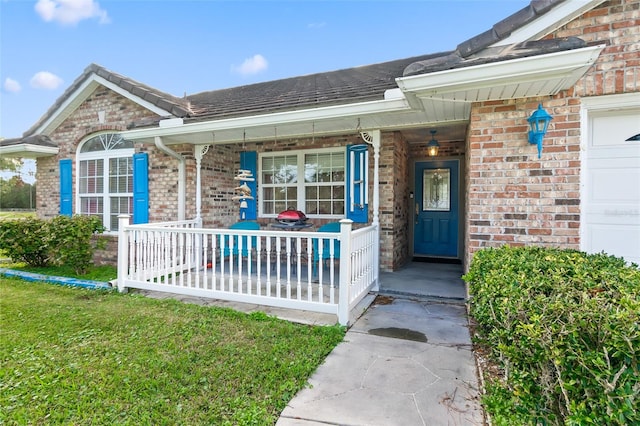 doorway to property featuring covered porch, a garage, and a lawn