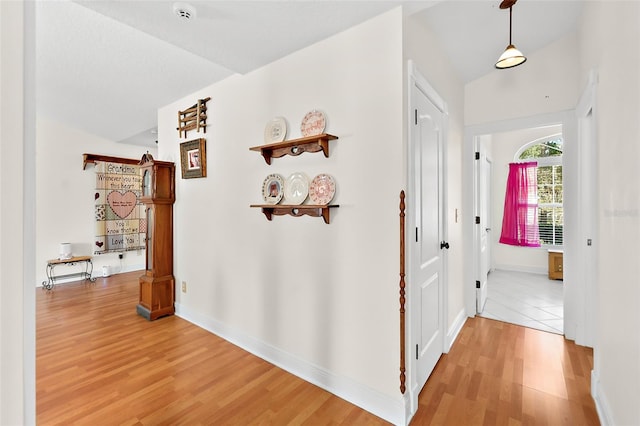 hall with lofted ceiling and hardwood / wood-style flooring