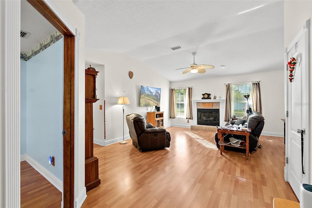 living room featuring a textured ceiling, ceiling fan, light hardwood / wood-style floors, and vaulted ceiling