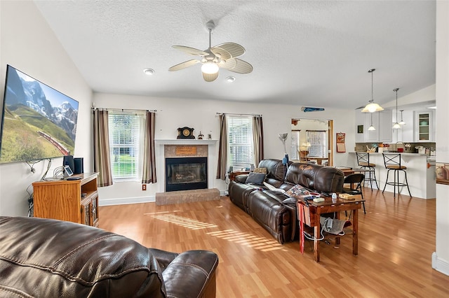 living room featuring a textured ceiling, ceiling fan, lofted ceiling, and light wood-type flooring