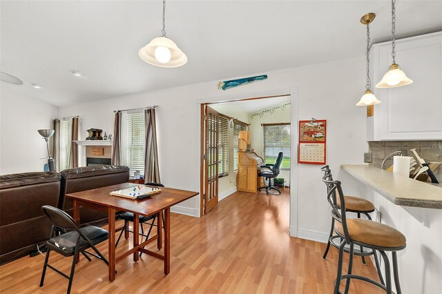 dining room featuring light wood-type flooring and vaulted ceiling