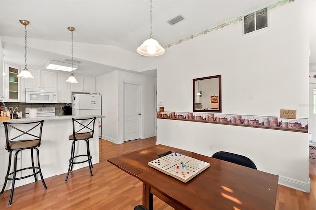 dining room featuring light hardwood / wood-style floors and vaulted ceiling