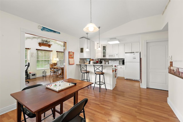 dining area with vaulted ceiling and light hardwood / wood-style flooring