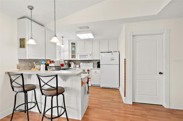 kitchen with lofted ceiling, kitchen peninsula, white cabinetry, and white appliances