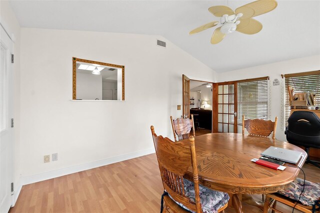 dining space with ceiling fan, french doors, wood-type flooring, and vaulted ceiling