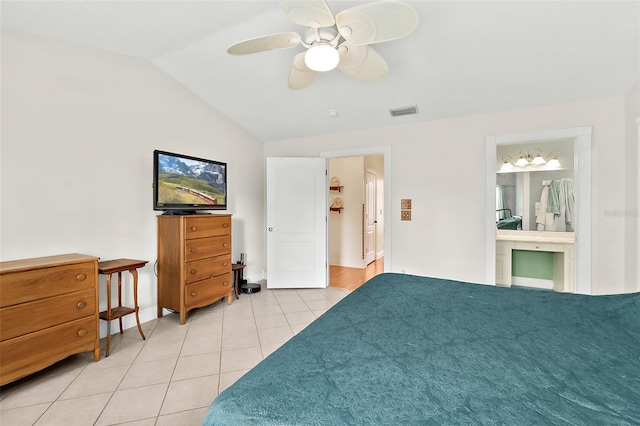 tiled bedroom featuring ceiling fan, vaulted ceiling, and ensuite bath