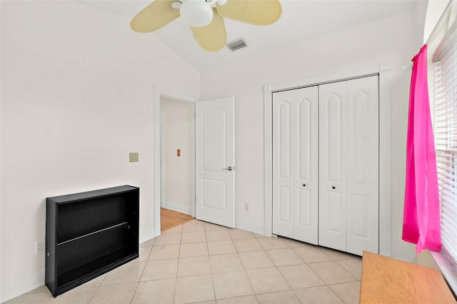 unfurnished bedroom with ceiling fan, lofted ceiling, light tile patterned floors, and a closet