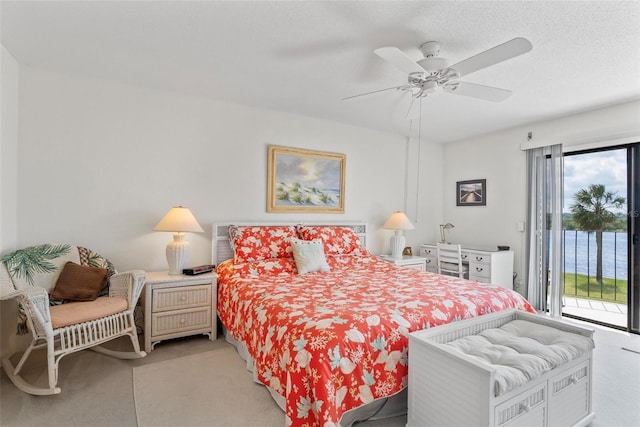 carpeted bedroom featuring access to outside, ceiling fan, a water view, and a textured ceiling