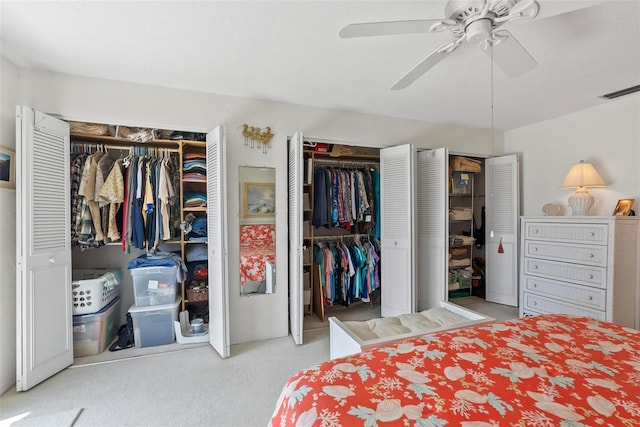 carpeted bedroom featuring ceiling fan and two closets