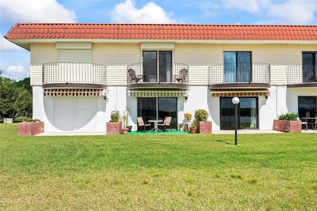 rear view of house featuring a lawn and a balcony