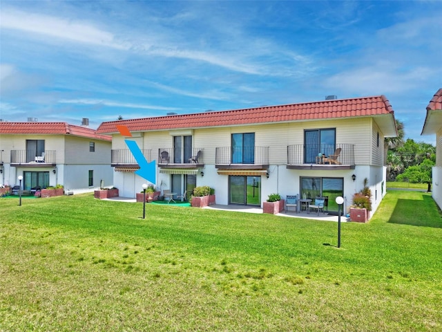 back of property with a yard, a balcony, and a patio area