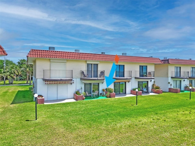 rear view of property with a yard and a balcony