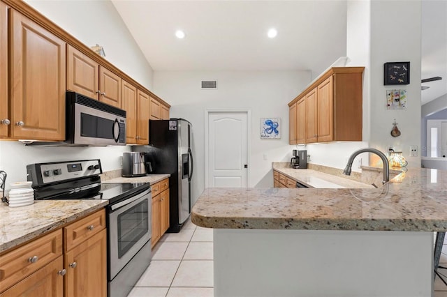 kitchen featuring light tile patterned flooring, a breakfast bar, vaulted ceiling, appliances with stainless steel finishes, and kitchen peninsula