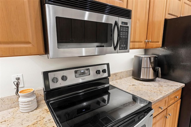 kitchen with light stone counters and appliances with stainless steel finishes