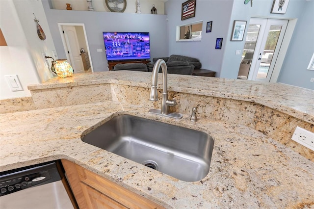 kitchen with light stone counters, dishwasher, sink, and french doors