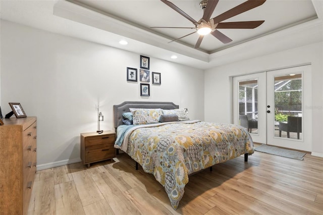 bedroom with ceiling fan, light hardwood / wood-style floors, french doors, access to outside, and a raised ceiling