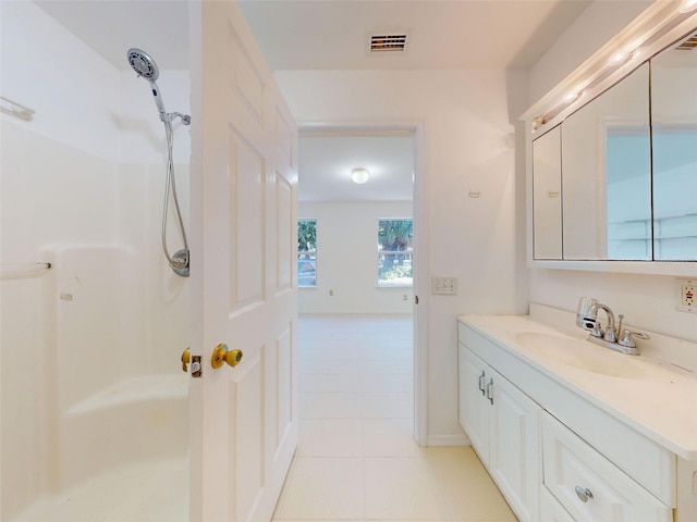 bathroom with a shower, tile patterned flooring, and vanity